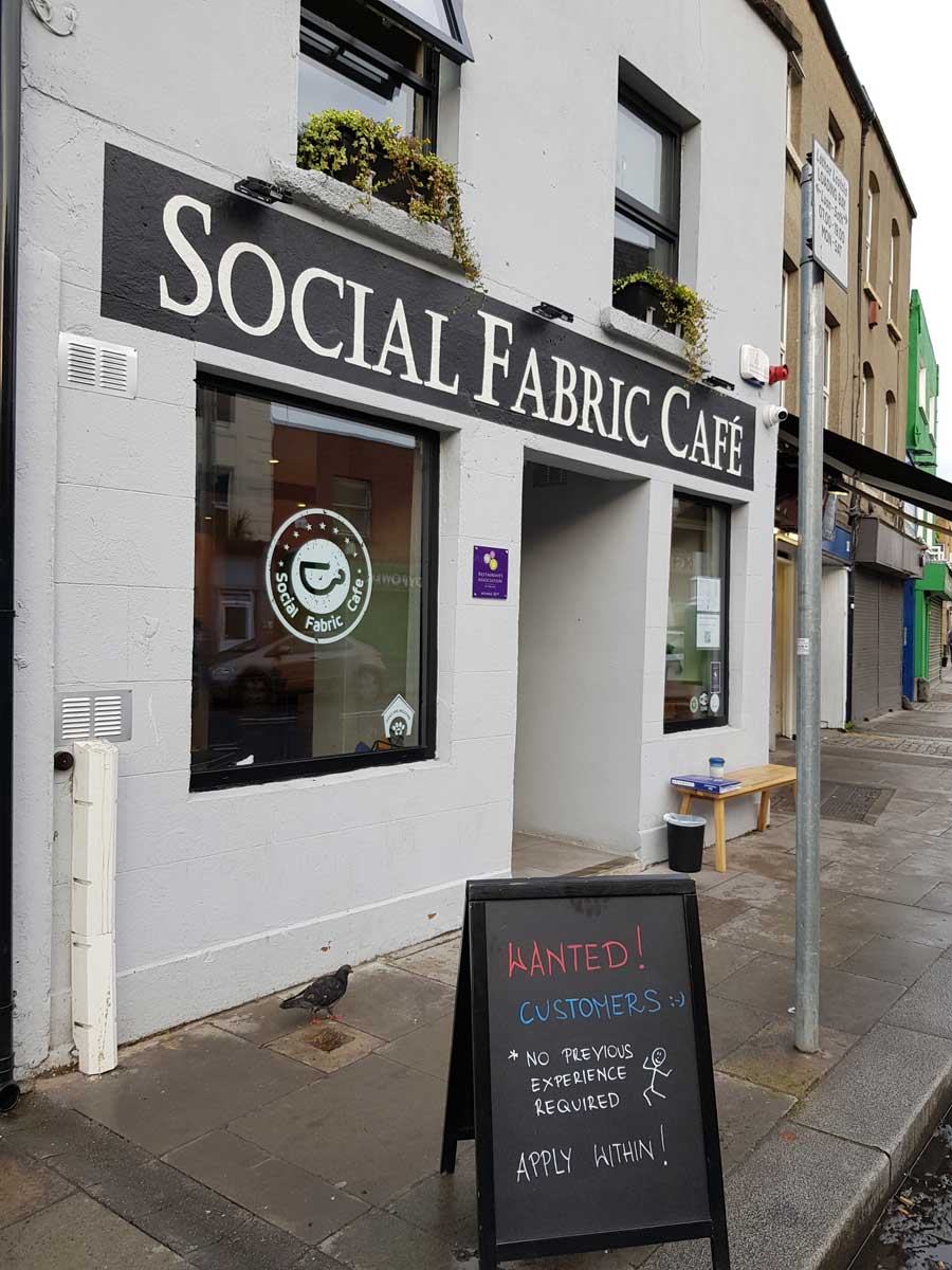 Exterior of Social Fabric Café with a sandwich board