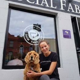 A staff member with a dog outside a Social Fabric Café 